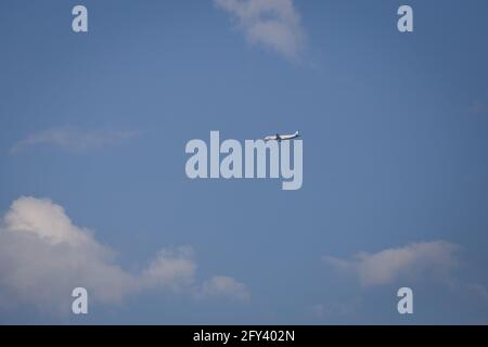 Propellerflugzeug von der Sonne gegen einen blauen Himmel beleuchtet Mit weißen Wolken und Baum - in Bewegung Stockfoto