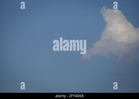 Propellerflugzeug von der Sonne gegen einen blauen Himmel beleuchtet Mit weißen Wolken und Baum - in Bewegung Stockfoto