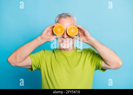 Porträt eines attraktiven fröhlichen grauhaarigen Mannes, der die Augen mit Orange schließt Stücke isoliert auf hellblauem Hintergrund Stockfoto