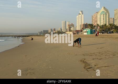 Erwachsene Frau, die in Strandsand schreibt, lokaler Tourist im Badeurlaub, North Beach, Durban Waterfront, Südafrika, Skyline der Stadt, Reiseziel Stockfoto
