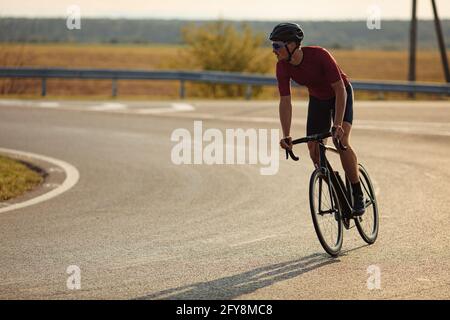 Junger Radfahrer, der Fahrrad auf Asphaltstraße fährt Stockfoto