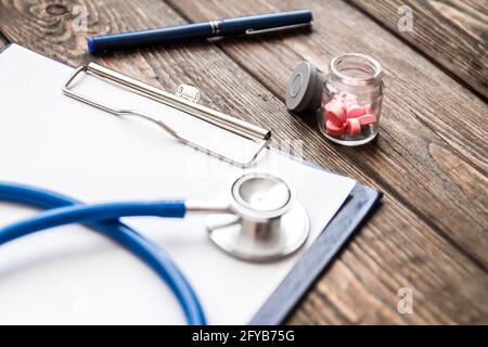 Krankenschein, Stethoskop und Pillen des Patienten auf dem Schreibtisch des Arztes Stockfoto