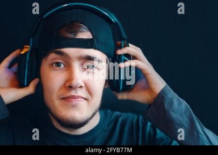 Kerl in der Mütze zieht seine Kopfhörer aus. Cyber-Sport. Young Handsome Spiel Streamer gewinnt schließlich eine Runde in einem wettbewerbsorientierten Spiel. Stockfoto