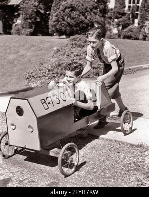 1930ER JAHRE 1940ER JAHRE EIN ERNSTHAFTER JUNGE, DER SEINEN ZWEITEN LÄCHELNDEN JUNGEN SCHOB BRUDER SITZT LENKUNG IHRER HAUSGEMACHTEN SOAP BOX DERBY RENNWAGEN - B16278 HAR001 HARS TEAMWORK WETTBEWERB FREUDE LIFESTYLE GESCHWINDIGKEIT ZUFRIEDENHEIT FEIER BRÜDER HAUS LEBEN KOPIEREN RAUM IN VOLLER LÄNGE INSPIRATION AUTOMOBIL MÄNNER RISIKO GESCHWISTER VERTRAUEN TRANSPORT B&W ERFOLG TRÄUME GLÜCK ABENTEUER DERBY SEINE STÄRKE IHR MUT AUTOS AUFREGUNG KRAFTVOLLEN FORTSCHRITT ERHOLUNG STOLZ GELEGENHEIT GESCHWISTER KONZEPTUELLE AUTOMOBILE ZWEITE STILVOLLE FAHRZEUGE ZUSAMMENARBEIT KREATIVITÄT WACHSTUM HAUSGEMACHTE JUGENDLICHE PRE-TEEN PRE-TEEN JUNGE ENTSPANNUNG Stockfoto