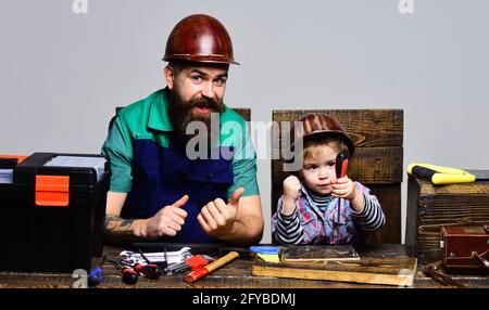 Konzentrierter Junge mit Vater, der zusammen repariert. Papa lehrt den kleinen Sohn, Werkzeuge zu benutzen. Vaterschaft, Reparatur, Assistenzkonzept. Stockfoto