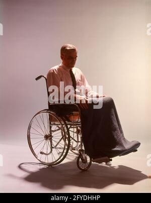 ANONYMER MANN AUS DEN 1960ER JAHREN, DER IM ROLLSTUHL SASS UND SCHATTEN AUF IHN WARF BODEN - KM1682 HAR001 HARS STUDIOAUFNAHME MOODY HEALTHINESS DISEARNESS DISABLED COPY SPACE GANZKÖRPEREIGNUNG PERSONEN MÄNNER RISIKO RÄDER TRANSPORT BEUNRUHIGT TRAURIGKEIT KRANKHEIT GESUNDHEIT SPIEGELN TRÄUME BERUF LEIDEN BEHINDERUNG WELLNESS PRÄVENTION BEHINDERUNG KRAFT HEILUNG SILHOUETTEN MUT DIAGNOSE HERAUSFORDERUNG ERHOLUNG GESUNDHEITSWESEN BEHINDERUNG BEEINTRÄCHTIGUNG STIMMUNG BEHANDLUNG GLUM FLUCHT UNGÜLTIG MOBILITÄTSUNTERSTÜTZUNG ANONYME ROLLSTÜHLE HINTERFRAGTEN ANSPRUCHSVOLLE KONZEPTE UNBEWEGLICHER LAP ROBE MITTELERWACHSENER MANN MIT MITTLEREM ERWACHSENEN Stockfoto