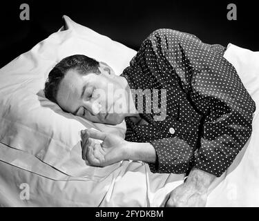 1940ER-JAHRE BRÜNETTE MANN FRIEDLICH SCHLAFEN AUF DER RECHTEN SEITE KOPF AUF KISSEN IM BETT MIT SCHLAFANZUG MIT PUNKTMUSTER - S10130 RCH001 HARS TRÄUME SCHLAF WELLNESS HOCHWINKEL POLKA KONZEPTIONELLE FLUCHT STILVOLLES SINNESBEWUSSTSEIN MID-ADULT MID-ADULT MAN ENTSPANNUNG DES GEISTES RUHEN SCHWARZ UND WEISSE KAUKASISCHE ETHNIE ALTMODISCH Stockfoto