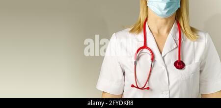 Arzt in medizinischer Schutzmaske und Anzug auf beigem Hintergrund. Kein Gesicht. Frau Stockfoto