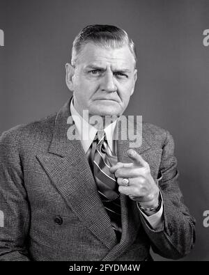 DER SENIOR BUSINESS MAN DER 1940ER JAHRE, STERN, ZEIGT MIT DEM FINGER AUF DEN GESICHTSAUSDRUCK UND BLICK AUF DIE KAMERA - S7677 HAR001 HARS KOMMUNIKATION SORGE LIFESTYLE GENERVT ÄLTESTER STUDIO SCHUSS MOODY MANAGER KOPIEPLATZ PERSONEN NACHDENKLICHE MÄNNER SENIOR MAN FÜHRUNGSKRÄFTE GESTIKULIEREN ÄLTERE ERWACHSENE AUSDRÜCKE BEUNRUHIGTE S&W BESORGT TRAURIGKEIT AUGENKONTAKT ANZUG UND KRAWATTE ALT ALTER OLDSTERS KOPF UND SCHULTERN OLDSTER BEKLEIDET IRAT UND STERN WARNGESTEN STIMMUNG BESCHÄFTIGT ÄLTERE CHEFS VERUNGLISTIGEN MISSFALLEN FEINDSELIGKEIT ZU ERMAHNEN AUFRICHTIGE FEIERLICHE BERATUNG ÄRGER EMOTION EMOTIONAL FOKUSSIERTEN ZEIGEFINGER INTENSIV DIE FÜHRUNGSKRÄFTE SIND NICHT SO SEHR AUF DIE VORTRÄGE DER MITARBEITER Stockfoto