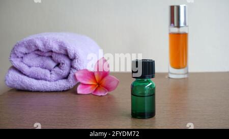 Spa-Öl, Frangipani-Blumen und Handtücher auf dem Tisch Stockfoto
