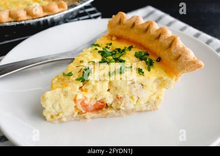 Garnelen-Quiche auf einem weißen Teller: Eine Scheibe Garnelen-Quiche auf einem kleinen Teller Stockfoto