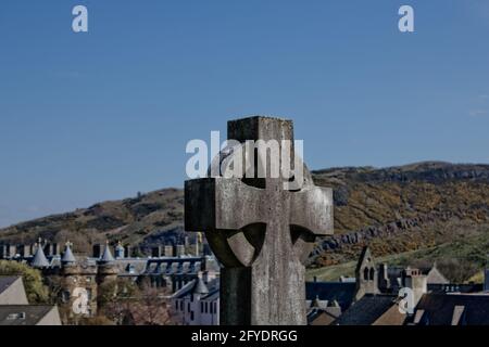 Ein keltisches Kreuzgrab mit Holyrood Palace und Park im Hintergrund, Edinburgh. Stockfoto