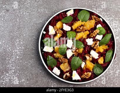 Rote Beete Salat mit Orangen, Walnüssen, Basilikum und Minze auf einem runden Teller auf dunklem Grund. Draufsicht, flach liegend Stockfoto