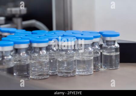 Viele medizinische Injektionsglasfläschchen mit blauer Oberseite und Flüssigkeit - Nahaufnahme Stockfoto