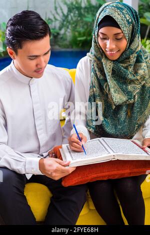 Asiatische muslimischen Mann lehre Frau lesen Koran oder Koran im Wohnzimmer Stockfoto