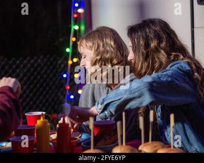 Junge Frau, die auf einer Party Cheeseburger isst Stockfoto