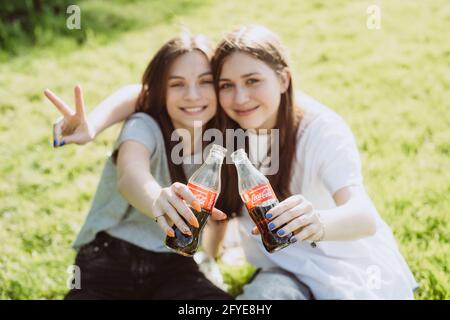 Bucha, Ukraine, 26. Mai 2021. Schöne junge Teenager an einem heißen Sommertag mit Glasflaschen Coca-Cola in den Händen und lächeln glücklich. Weich Stockfoto