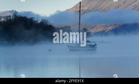 Die Yacht liegt an einem nebligen Morgen auf dem Lake Wakatipu in Glenorchy, Otago, Südinsel, Neuseeland. Stockfoto