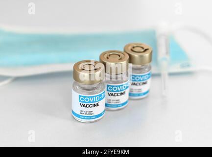 Nahaufnahme mit selektivem Fokus auf Vials, Maske und Spritze mit generischem Covid-Impfstoff auf weißem Hintergrund. Stockfoto