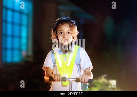 Kind in reflektierender Weste in der Dunkelheit. Sicherheit auf dunklen Straßen der Stadt für Schulkinder. Sicher nach Hause in der Nacht oder am Abend. Stockfoto