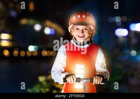 Kind in reflektierender Weste in der Dunkelheit. Sicherheit auf dunklen Straßen der Stadt für Schulkinder. Sicher nach Hause in der Nacht oder am Abend. Stockfoto