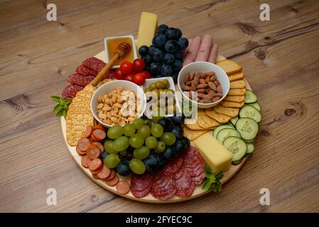 Platte mit leckeren Snacks: Käse, Cracker, Honig, Obst und Nüsse Stockfoto