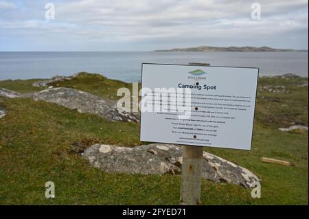West Harris Trust Campingplatzschild mit Informationen. Verschwommener Hintergrund von Gras, Felsen, Meer und Himmel. Camping-Spots, die auf Straßenrand par Stockfoto