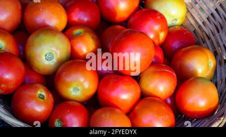 Nahaufnahme frischer roter Tomaten auf dem Markt in Jaipur, Indien. Tomaten mit Schüssel auf einem verschwommenen Hintergrund Nahaufnahme Stockfoto