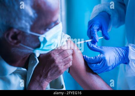 Ältere ältere Patienten mit Maske, die eine Impfung oder einen Jab erhalten Krankenhaus - Arzt in Schutzkleidung Hazmat Anzug Behandlung Covid Patienten Injektion antiviral Stockfoto