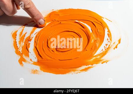 Spreizen Sie mit dem Finger ein orangefarbenes Acrylglas Stockfoto