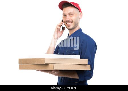 Horizontales mittleres Porträt eines gutaussehenden jungen kaukasischen Pizza-Typen mit Boxen, die am Telefon sprechen und auf die Kamera blicken, weißer Hintergrund Stockfoto