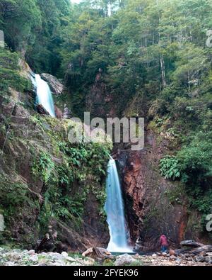 Aufnahme eines Wasserfalls mit doppeltem Sturz auf der Straßenseite Stockfoto