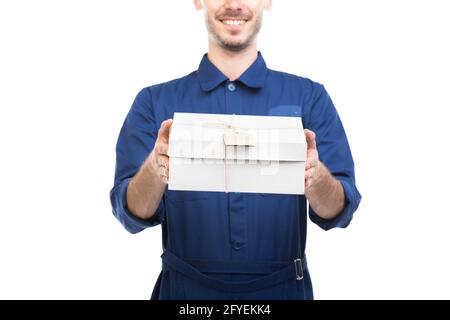 Horizontales mittleres Porträt eines hübschen jungen erwachsenen kaukasischen Delivery Mann trägt blaue Uniform Holding-Box, weißem Hintergrund Stockfoto