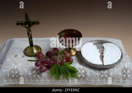 Das Konzept des Fronleichnamsfestes. Heilige Kommunion und Tasse Glas mit Rotwein auf dem Tisch. Stockfoto