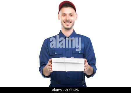 Horizontales mittleres Porträt eines hübschen jungen erwachsenen kaukasischen Delivery Mann trägt blaue Uniform Holding-Box, weißem Hintergrund Stockfoto