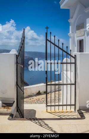Blick auf die griechische Insel aus dem Kirchenhof mit Toren im Vordergrund mit Blick auf das Meer. Aufgenommen auf der Insel Santorini, Griechenland Stockfoto