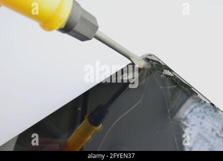 Den Touchscreen des Tabletts mit einem Schraubendreher beschädigen Stockfoto