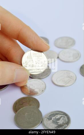 Beschnittene Hand mit 1 Thai Baht Münze auf weißem Hintergrund Stockfoto