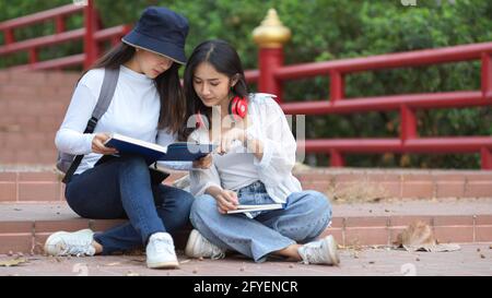 Porträts von zwei weiblichen Studenten, die entspannt zusammen lesen Sitzen auf der Treppe in der Universität Stockfoto