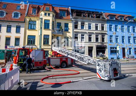 Rostock, Deutschland. Mai 2021. Feuerwehrleute sichern das Wohn- und Geschäftsgebäude im Stadtzentrum, das bei einem Brand stark beschädigt wurde. In einem Batterienfachgeschäft war am 27.05.2021 ein Brand ausgebrochen. Nach Angaben der Polizei war es nach ersten Erkenntnissen bei Reparaturarbeiten an einer Batterie zu einer Entzündung gekommen. Quelle: Jens Büttner/dpa-Zentralbild/dpa/Alamy Live News Stockfoto