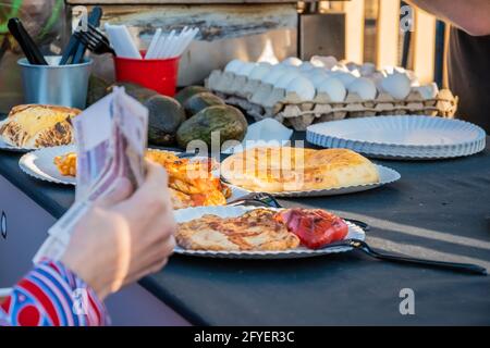 Aus der Nähe einer Frau mit einer Papierwährung bestellt ein Kunde am Schalter eines mexikanischen Restaurants unter freiem Himmel. Food Festival in Th Stockfoto