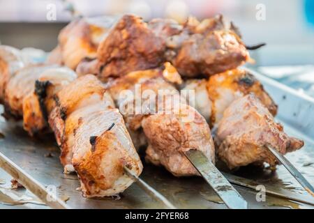 Gebratener Shish Kebab auf Spiessen an der Theke eines Straßenrestaurants. Food Festival im Stadtpark. Street Fast Food. Selektiver Fokus, geringe Tiefe o Stockfoto