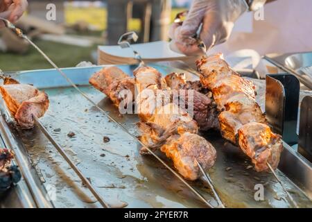 Gebratener Shish Kebab auf Spiessen an der Theke eines Straßenrestaurants. Food Festival im Stadtpark. Street Fast Food. Selektiver Fokus, geringe Tiefe o Stockfoto