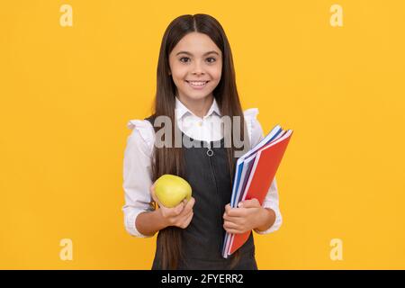 Beginnen wir damit, für eine bessere Zukunft zu lernen. Glückliches Kind lächelt mit Apfel und Büchern. Informieren Sie sich noch heute Stockfoto