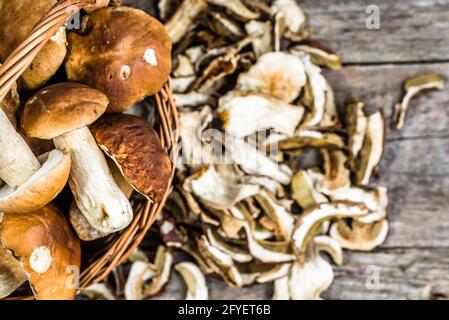Frische Steinpilze in einem Korb und getrocknete Pilze Holztisch von oben Stockfoto