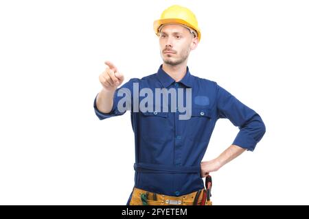 Horizontales mittleres Porträt eines modernen hübschen jungen kaukasischen Ingenieurs mit blauer Uniform und Zeigefinger auf etwas weißen Hintergrund Stockfoto
