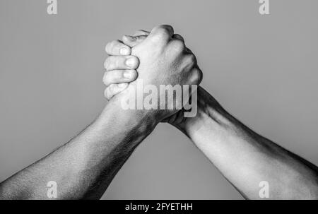 Freundlicher Händedruck, Freundschaftsgrüße, Teamarbeit, Freundschaft. Handschlag, Waffen, Freundschaft. Vergleich der Handrivalität mit der Herausforderung. Stockfoto