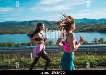 Zwei schöne, fröhliche Mädchen, die an sonnigen Tagen im Freien laufen und gesund und schlank bleiben Stockfoto