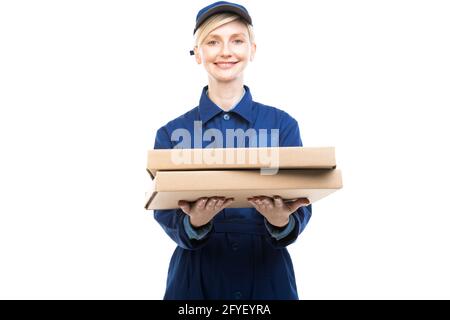 Horizontales mittleres Porträt des modernen schönen kaukasischen Lebensmittel Lieferers trägt blaue Uniform halten Pizzakartons, weißer Hintergrund Stockfoto