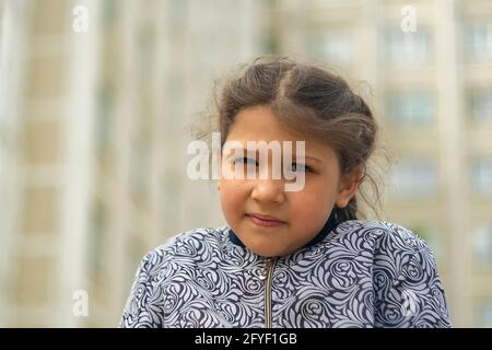 Mädchen 8 Jahre alt gegen Gebäude. Tag, horizontale Aufnahme Vorderansicht. Stockfoto